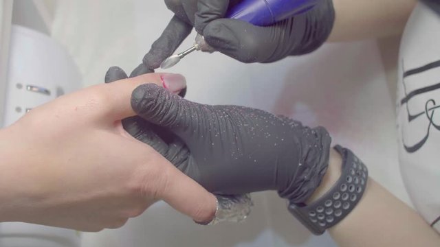 The manicurist removes the old shellac from the client's nail. Beginning of the manicure procedure in the beauty salon