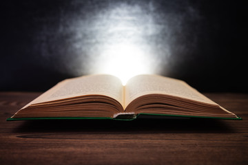 On the beautiful boards is an open book. Illumination of the book. Black background. Day of knowledge. Hello. school. September 1.