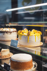 The girl waiter fills the confectionery showcase, placing her cakes and pastries, a view through the glass of the refrigerator for desserts.cake and people in cafe concept.