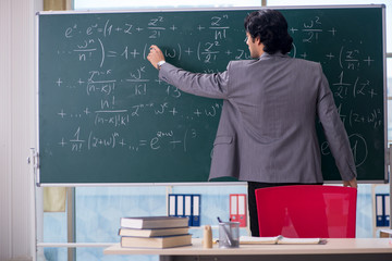 Young handsome math teacher in classroom