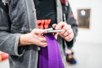 Close Up On Man Using Smartphone App On Training Bjj Gi