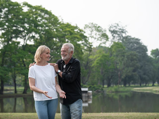 A happy senior couple stand in a park on a sunny day. Relax in the forest spring summer time. free time, lifestyle retirement grandparents concept