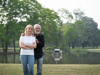 A happy senior couple stand in a park on a sunny day. Relax in the forest spring summer time. free time, lifestyle retirement grandparents concept