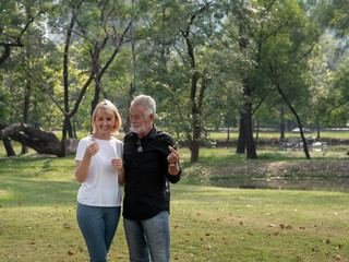 Happy senior man and woman couple in a park on a sunny day. relax in the forest spring summer time. free time, lifestyle retirement grandparents concept.