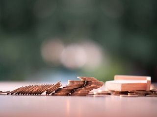 Money coins stacks with model house falling on nature green background and sunlight. Finance and house loan, refinance, Property Investment and business, bankruptcy, credit concept. with copy space