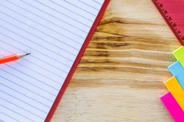 School and drawing supplies, on wooden table. Exercises book, pencils, sticky note and ruler. With...