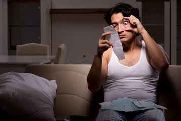 Fototapeta premium Young man calculating expences night at home