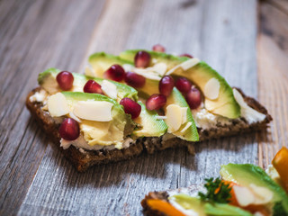 Delicious and healthy avocado toast with pomegranate, bell pepper and almond