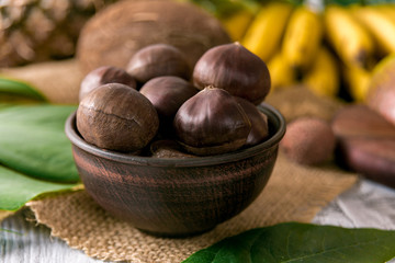 Roasted chestnuts served in chestnut pan on an old table