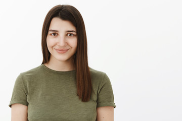 Close-up shot of happy charming and tender cute young 20s brunette in olive t-shirt smiling shy and energized at camera feeling optimistic gazing trustworthy at camera over white background