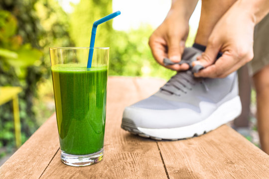 Green Smoothie. Man Tying Shoe Next To Healthy Drink.