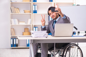 Young handsome employee in wheelchair at the office