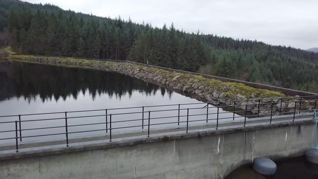 Aerial reveal of the impressive Gleann Dubh Reservoir surrounded by cloud shrouded mountains in Scotland, UK