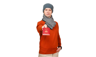 The man in an orange sweater, a scarf and a cap stretches the Russian international passport on a white background