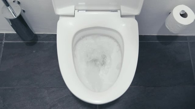 Fresh water being flushed down in a toilet, view from above.