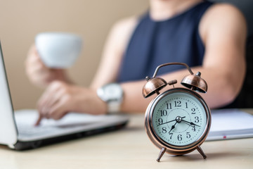 Close up alarm clock with young Businesswoman using laptop analysis marketing plan and drinking coffee in the morning. Business, Finance and lifestyle concepts