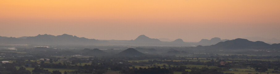 Panorama or wide angel view of small city in front of the mountains in Thailand with beautiful evening sky.