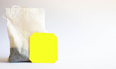Yellow label tea bag placed on white-grey background shot in studio.