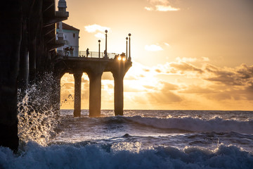 Wave breaking by pier at Manhattan Beach, California at sunset