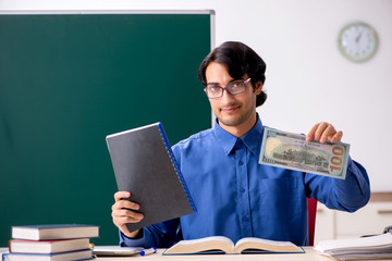 Young male teacher in front of chalkboard