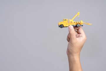 Hand holding emergency tow truck toy car