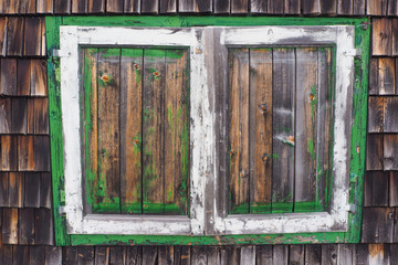 old wooden window shutters of a wooden alpine hut  with colors flaking off