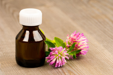 essential clover oil in brown glass bottle on wooden rustic table