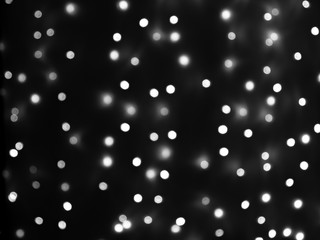 Defocused lights of Christmas garland in black and white evenly distributed over the area of the frame, background, texture