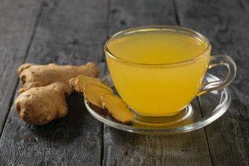 Drink ginger root, lemon, orange, honey and cinnamon on a black table.