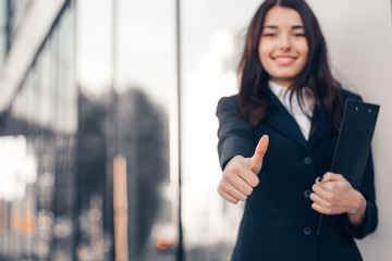 Successful smile businesswoman or entrepreneur shows thumbs up standing in front of his office.