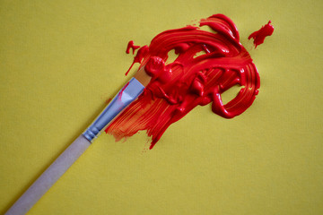 Red paint with brush against yellow background
