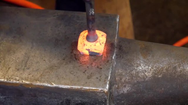 A Metal Worker Fullering a Divet in a Block of Hot Steel in the Hardy Hole in the Blacksmith Shop
