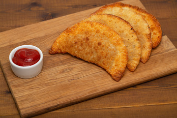 Freshly cooked chebureki on a wooden background. Chebureki fried pie with meat and onion. Pastries empanadas