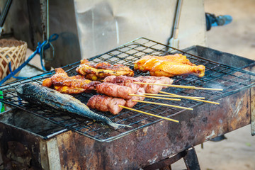Grilled beach food for sale including fishes, chicken, sausages at beach market shop, Naiyang beach, Phuket, Thailand.