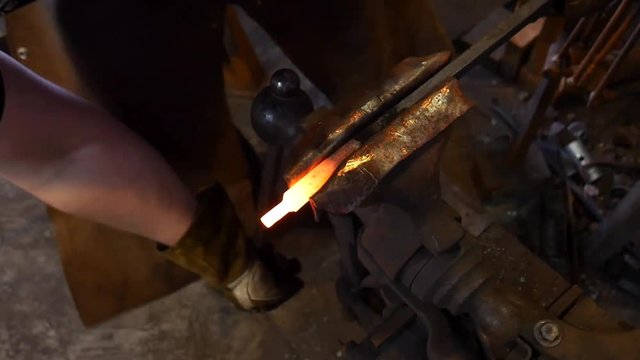 A Blacksmith Forging a Tennon on a Hot Metal Bar of Iron