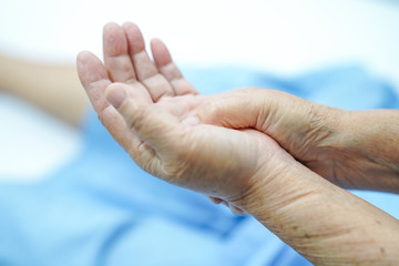 Asian senior or elderly old lady woman patient feel pain her hand on bed in nursing hospital ward :...