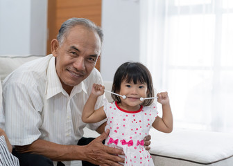 togetherness of a grandfather with her little princess holding music instrument look at the camera...