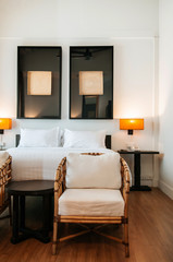 Asian contemporary vintage hotel bedroom with bed, white sheet, pillows, rattan chairs