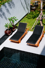 Outdoor hotel furniture modern sunbeds by pool side and garden, top view