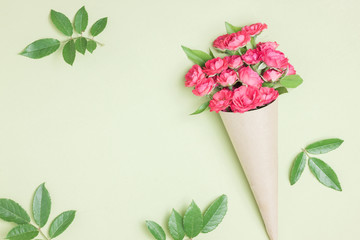 Bouquet of small red roses in vintage paper on the table.