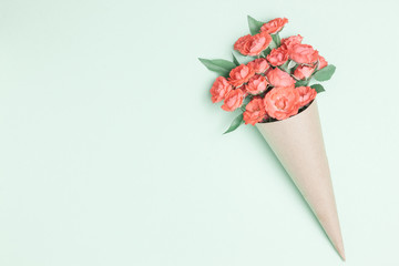 Bouquet of small red roses in vintage paper on the table.