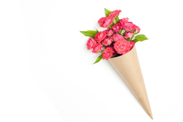 Bouquet of small red roses in vintage paper on the table.