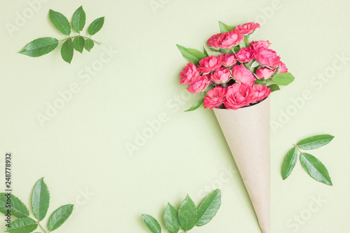 Bouquet of small red roses in vintage paper on the table.