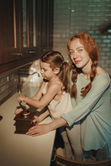 beautiful happy mom and daughter cook in kitchen