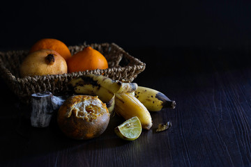 Rotten and withered fruits on brown wooden table and in old basket which has dim light