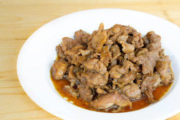 Stir fry pork slice with sugar (Sweet pork) in white dish on wooden table, delicious Thai food Asia food