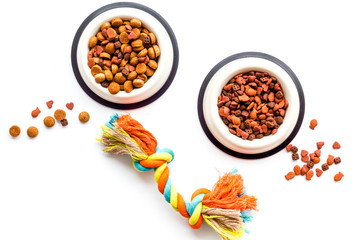 Pets accessories in home. Dog food in bowl and toys on white background top view