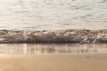 Small waves are approaching the beach. Causing the division between sand and sea.