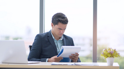 Young business people read the paper with a serious and unhappy expression at the office.