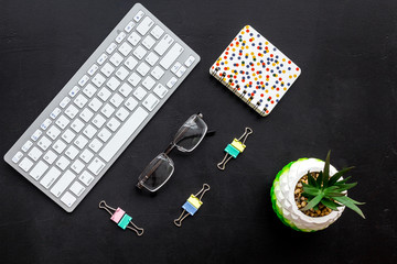 Work desk of manager. Computer keyboard, glasses, stationery, plant on black background top view space for text